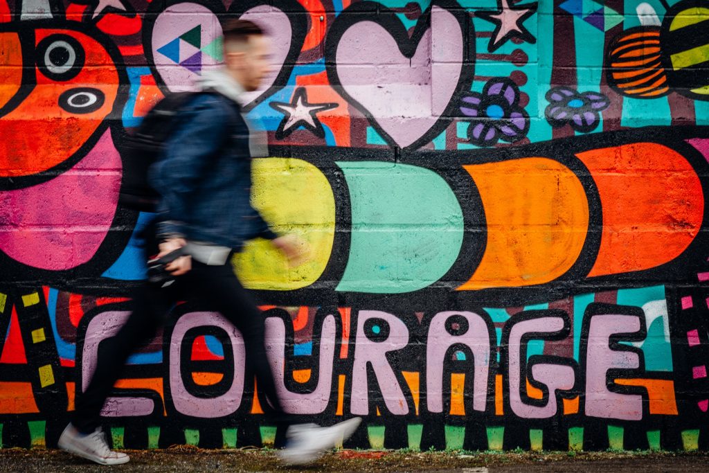 Courage graffiti as person walks past